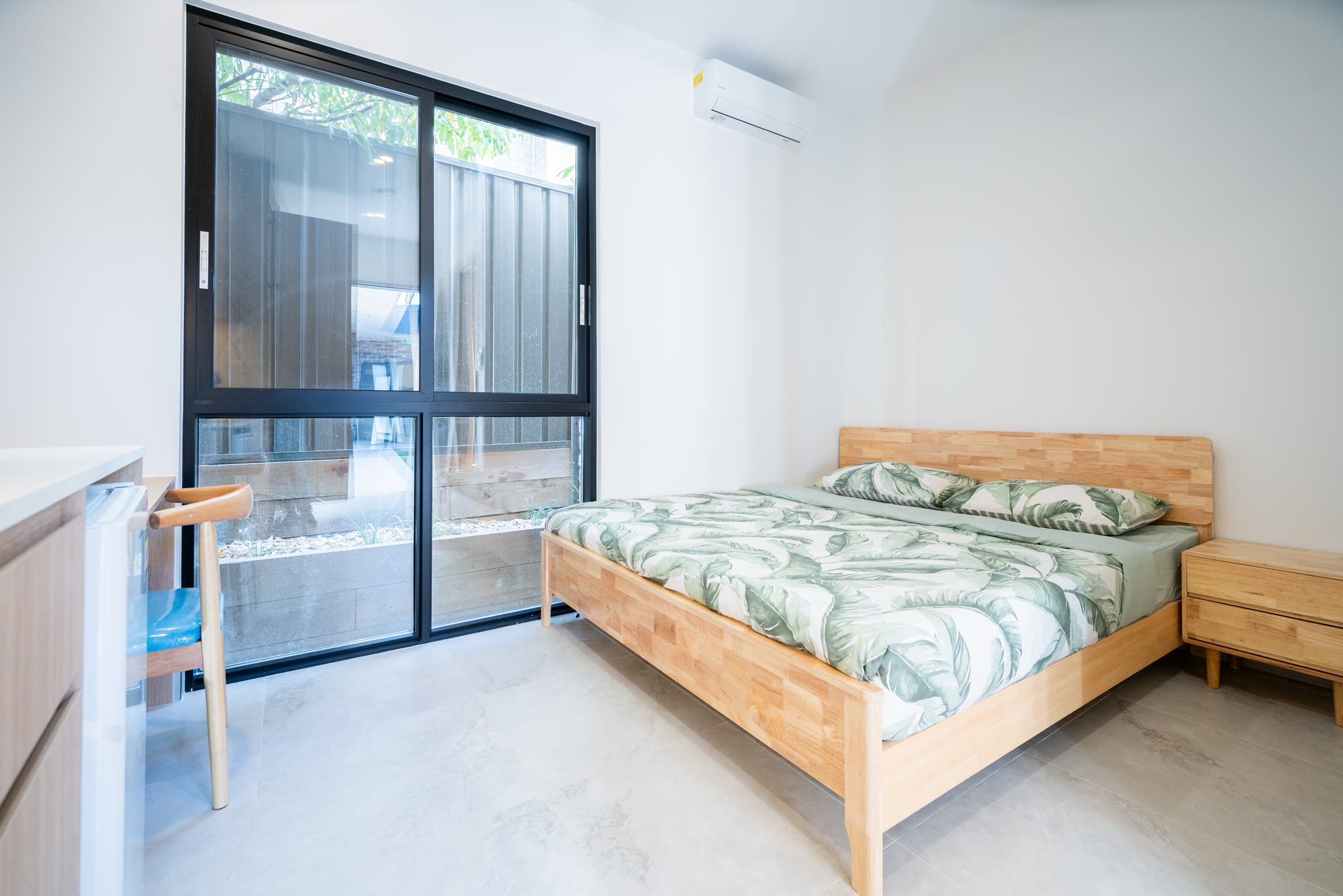 A finished bedroom in a co-living home in Western Sydney with its own wall-mounted split system air conditioner above the bed